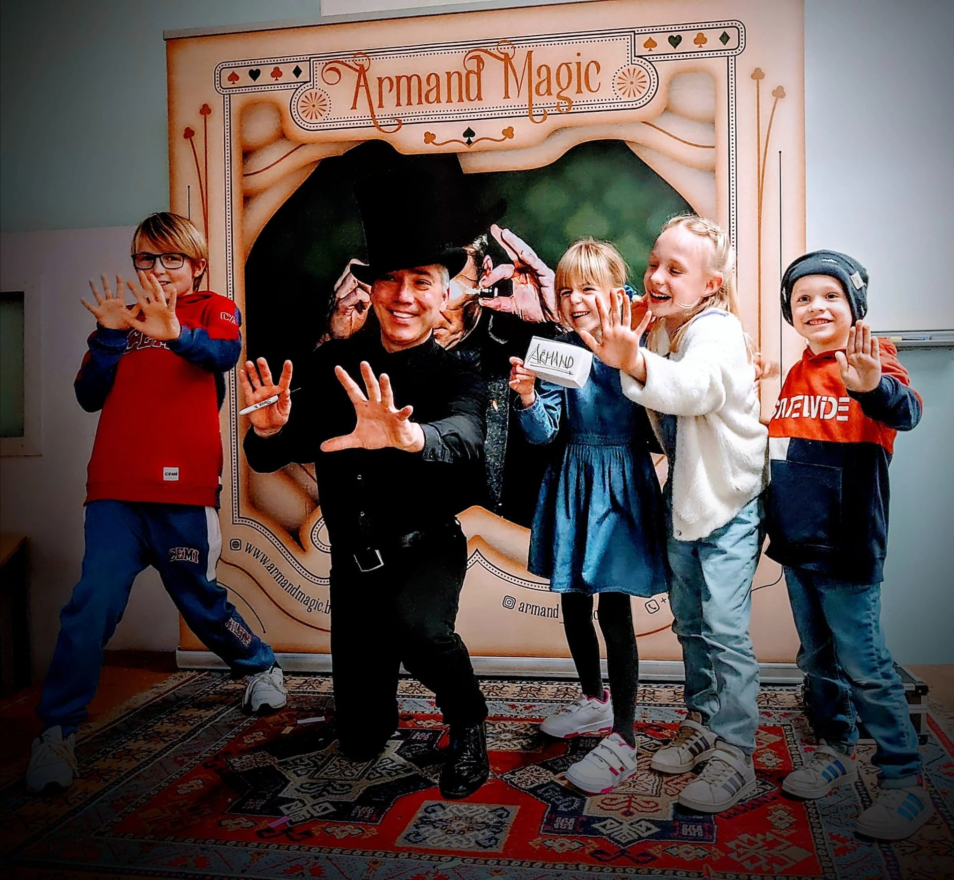 Kinderen steken lachend hun handen op naast Armand Magic na de goochelshow