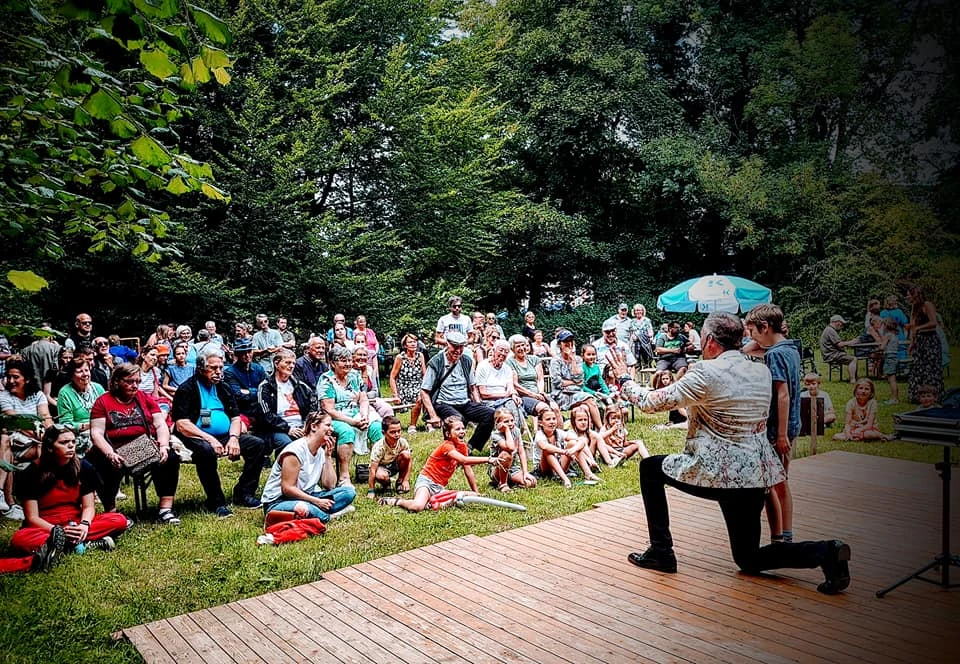 Armand Magic betrekt een jonge vrijwilliger bij zijn act tijdens een openluchtvoorstelling